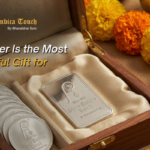 Silver coins and bars by Shree Ambica Touch displayed in a wooden box with marigold flowers, symbolizing auspicious gifting for 2026 weddings and celebrations.